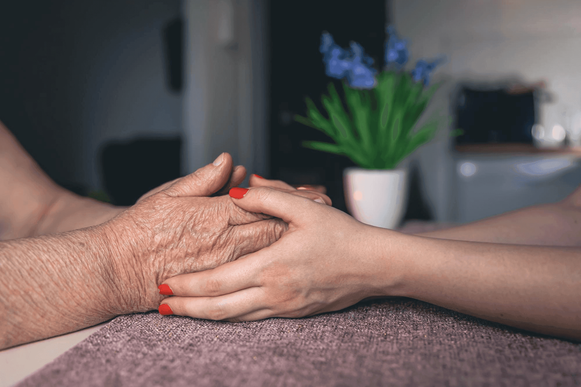 Young hands gently holding elderly hands — compassion and care